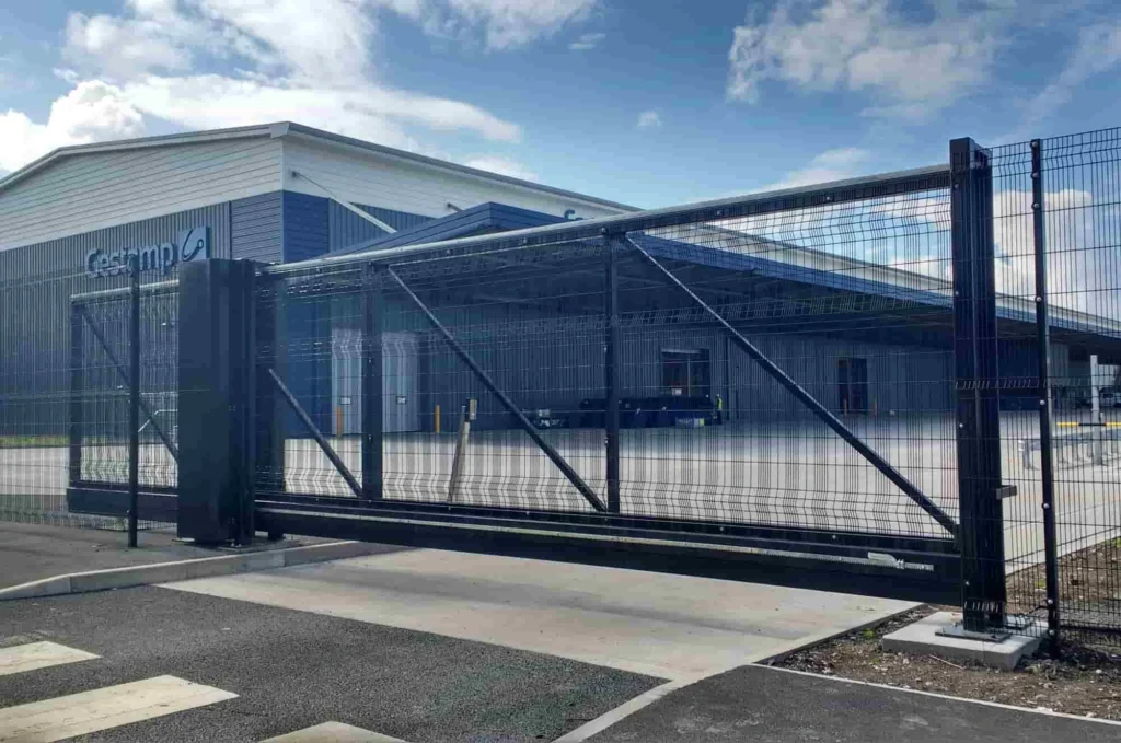 A large commercial sliding gate in operation with a factory backdrop.
