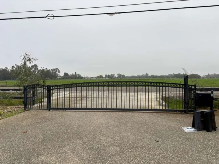 Black metal sliding barrier, identified as an automatic gate making noise.