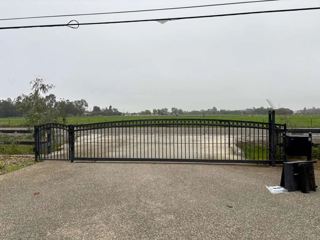 Black metal sliding barrier, identified as an automatic gate making noise.