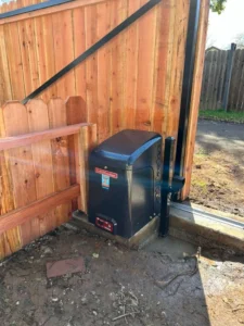 A modern black LiftMaster automatic gate operator is securely installed next to a cedar wood fence. Sacramento gate repair is seen here.