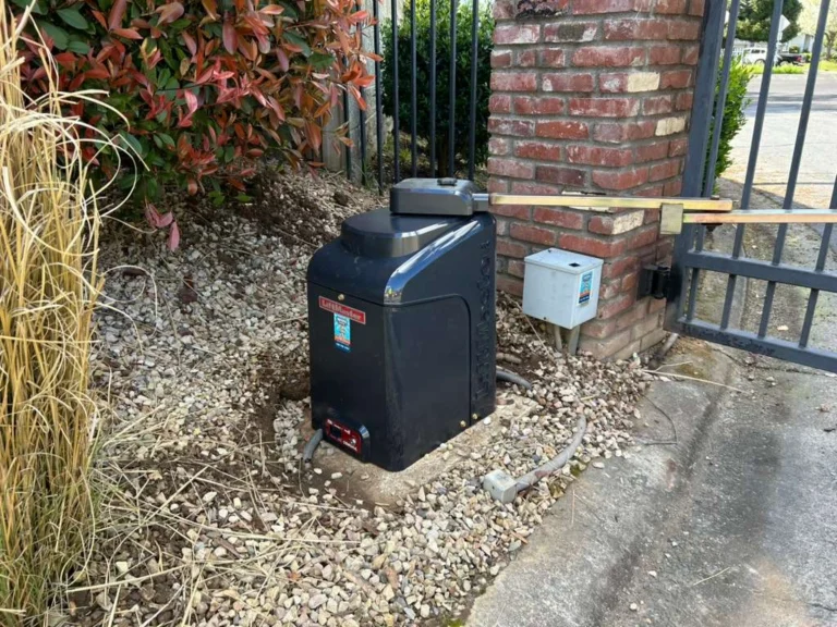 A dark gray LiftMaster automatic gate opener installed near a brick pillar, highlighting LiftMaster vs DoorKing gate operators.